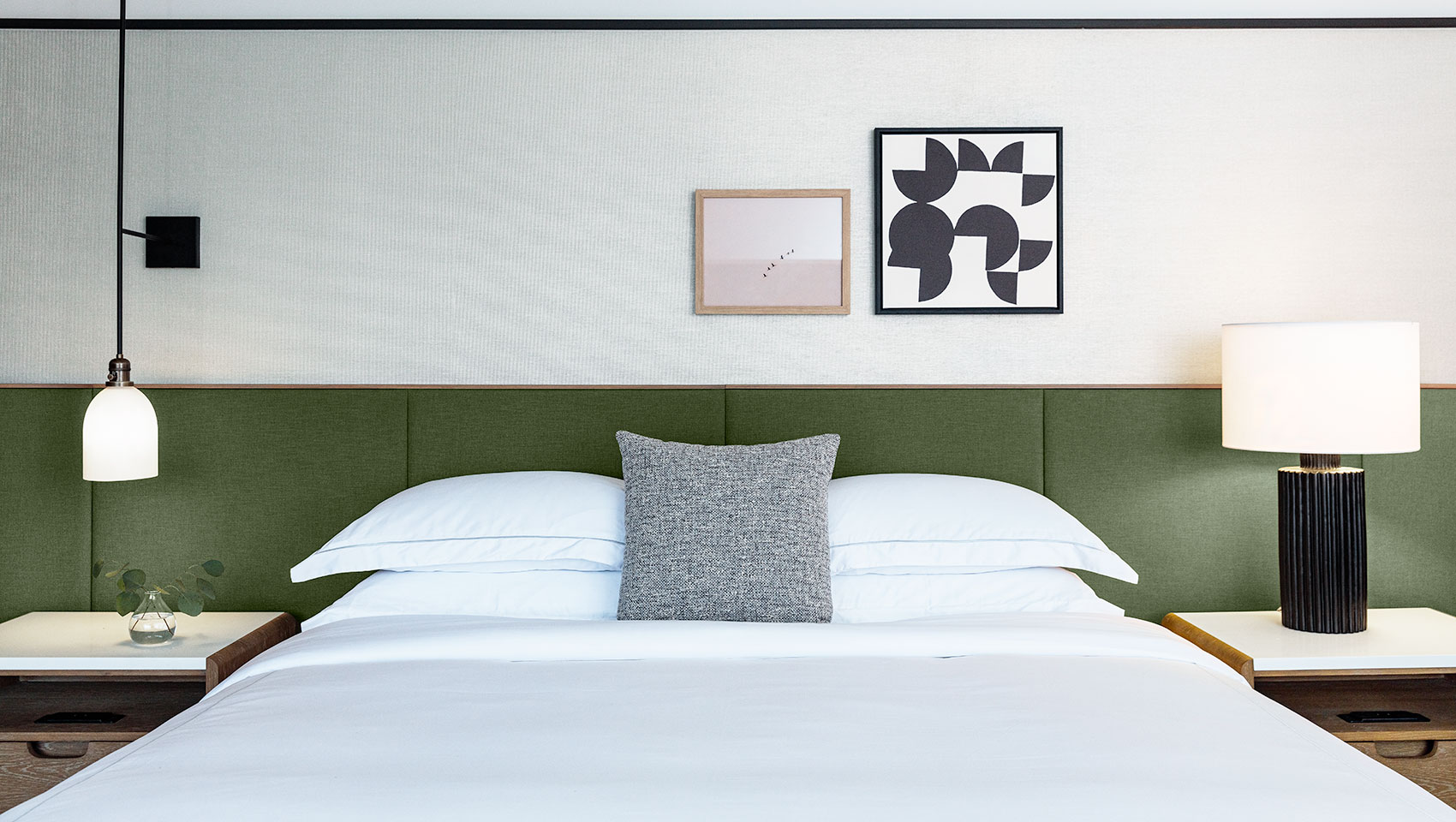 large king guestroom with art on the wall and a green headboard